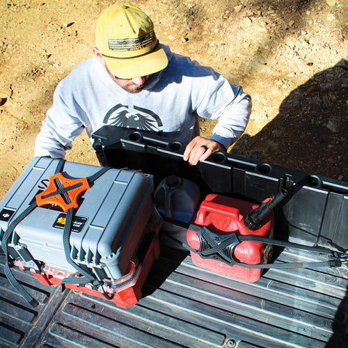 Person organizing tools in a large black toolbox on a truck bed.