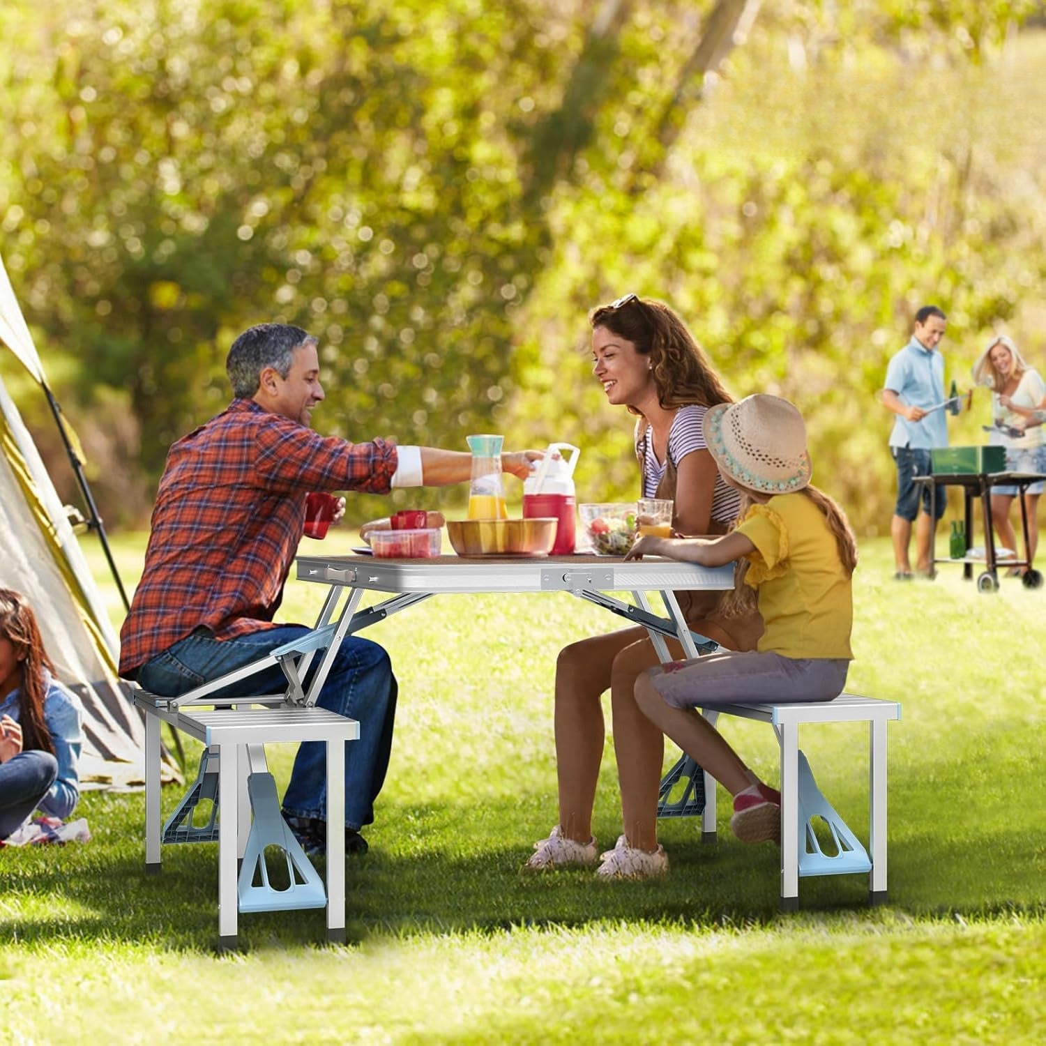 Family having a picnic in a park with tents and people in the background