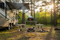 Foldable outdoor BBQ grilling table set up at a campsite next to an RV